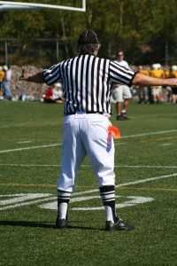 Football referee with arms outreasched to both sides which symbolizes what churches should think about when choosing church membership software and why one is better over the other for that church