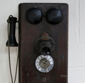 Antique brown phone hanging on the wall.