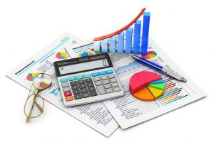 Calculator, pen and glasses on top of reports with 3D pie chart and bar graph