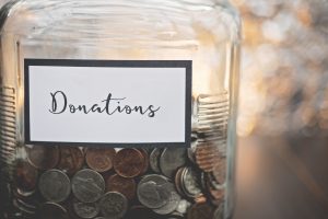 glass jar labeled donations filled with various coins