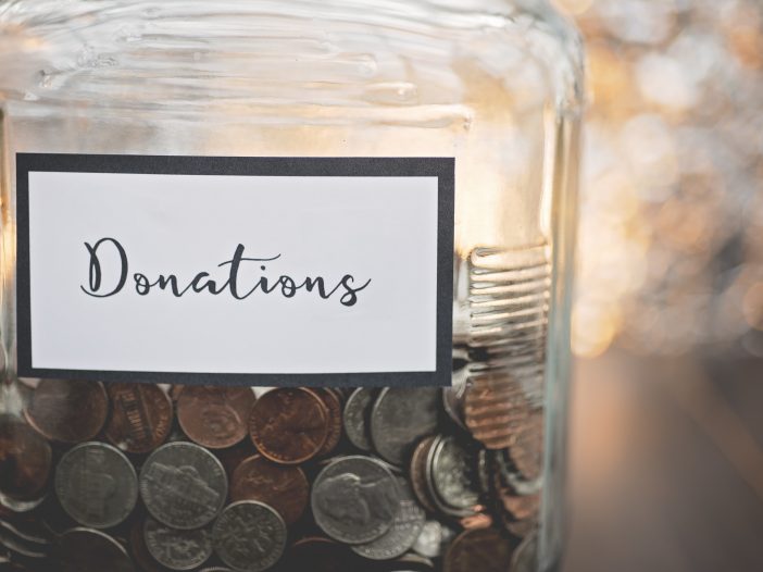 glass jar labeled donations filled with various coins