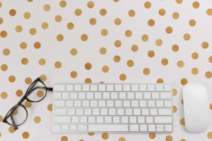 white computer mouse and keyboard, black eyeglasses on gold and white polkadot background