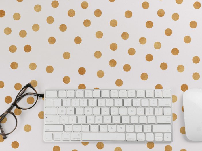 white computer mouse and keyboard, black eyeglasses on gold and white polkadot background