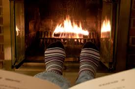 Person reading cozy up next to a fire