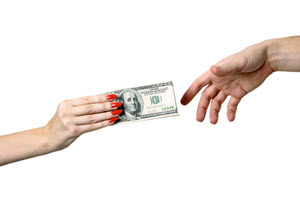 A man's hand handing one hundred dollar bills to a woman's hand.