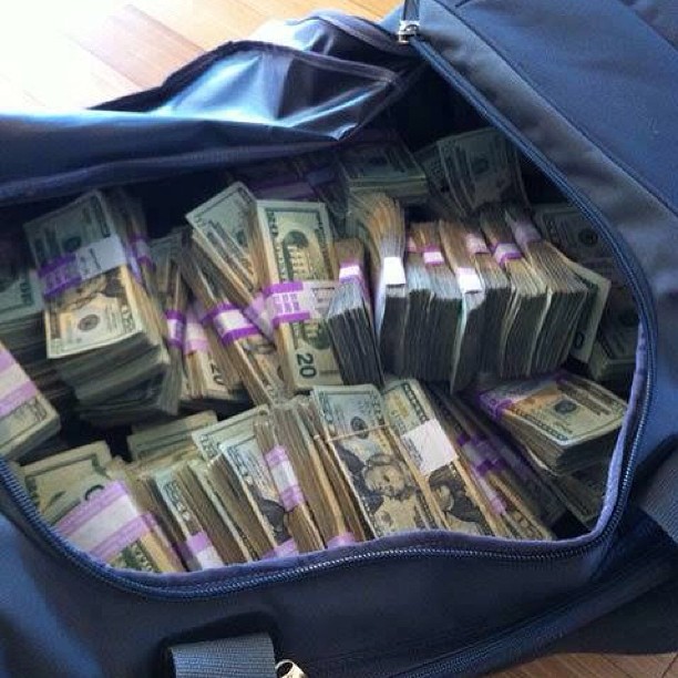 A blue bag of money with 20's banded together and open.