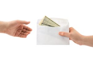 Envelope of 100 dollar bills being handed from one person to another.