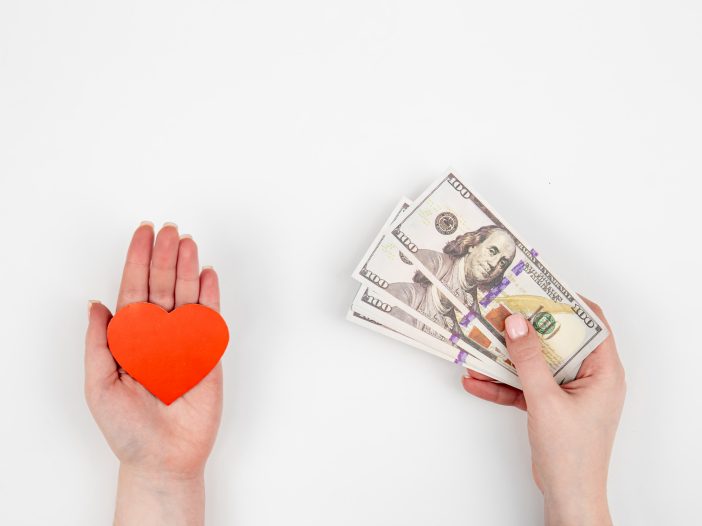 One Hand with paper heart and one hand with money on a white background