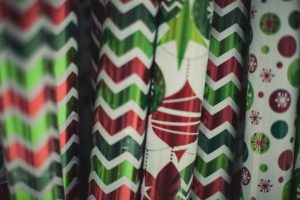 Several red, green, and white Christmas wrapping paper tubes with zigzag stripes, polka dots and ornament prints