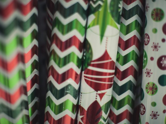 Several red, green, and white Christmas wrapping paper tubes with zigzag stripes, polka dots and ornament prints