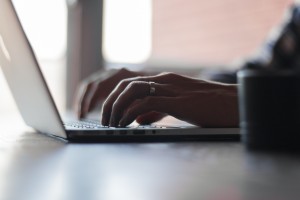 shows two hands typing on a laptop computer.