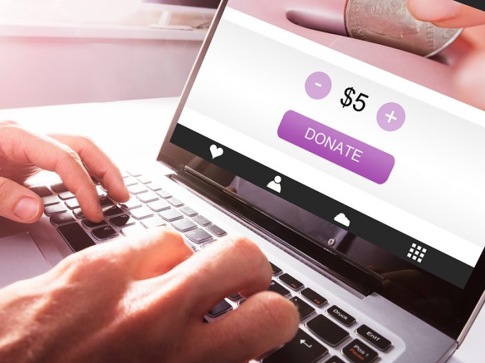 Close-up Of A Man's Hand Using Laptop To Donate Money online