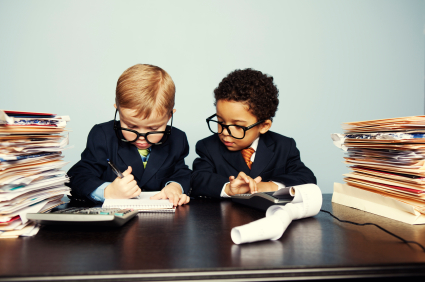 Two kids in suits with stacks of accounting records and a calculator in front of them working on taxes for churches