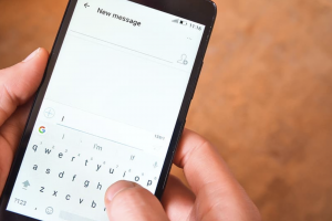 text messaging with mobile device. it shows the cell phone and a person typing into it.