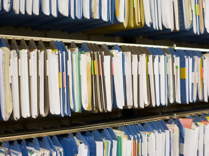 shelf full of file folders filled with documents that are replaced with software programs for church