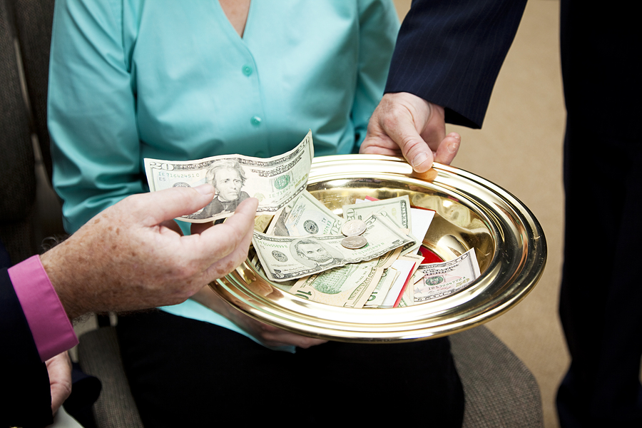 Church donation received in offering plate with several people gathered around.